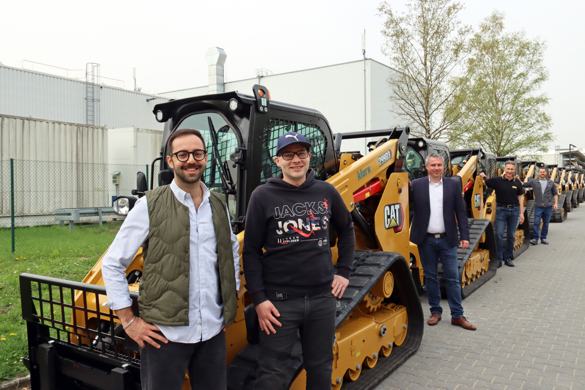 Alessio Pala und Sven Blanke aus dem klarx Team vor 15 CAT Deltaladern im Münchner Logistikzentrum von klarx